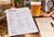 Foambyte printable brew day recipe summary and handwritten batch notes on a brewery table